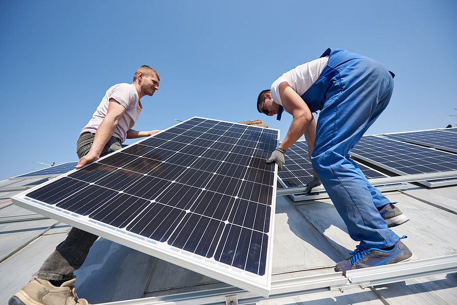 two workers carrying the solar panel